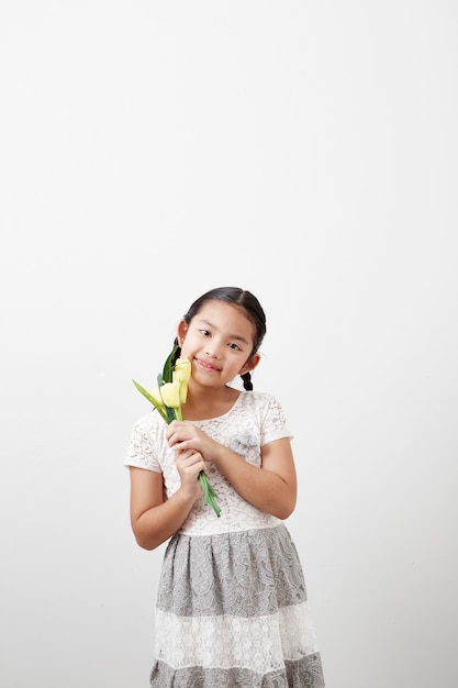 Meisje dat gele tulpen op wit houdt