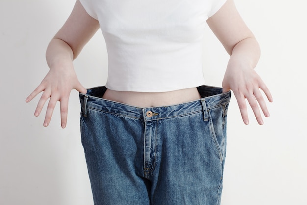 Meisje dat haar grote jeans trekt en gewichtsverlies toont