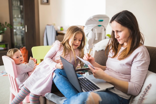 Meisje dat haar moeder bekijkt die aan laptop werkt