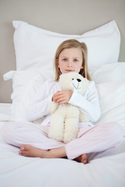 Foto meisje dat haar teddy op het bed koestert