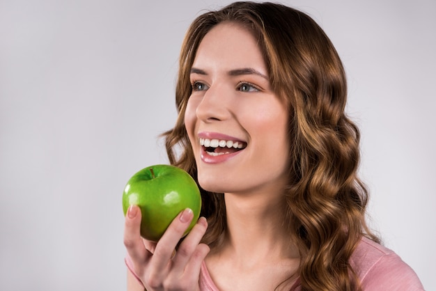 Meisje dat het groene appel geïsoleerd glimlachen houdt.