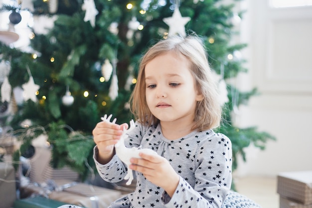 Meisje dat het huis met Kerstboom en Kerstmisdecor verfraait.