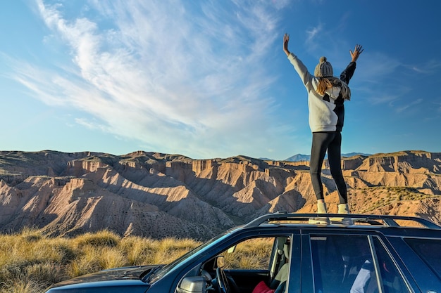 Meisje dat het woestijnlandschap observeert, klom op het dak van een offroad-vrachtwagen