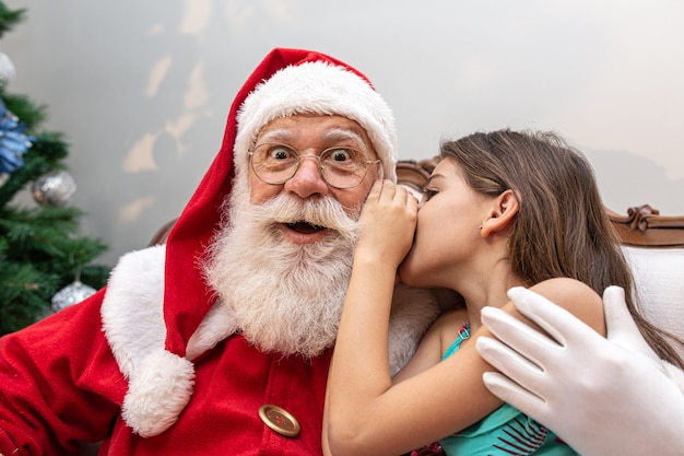 Meisje dat in het oor van de kerstman fluistert