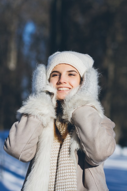 Meisje dat in hoed en vuisthandschoenen in de winter glimlacht