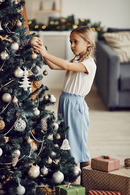 Meisje dat Kerstboom met speelgoed verfraait