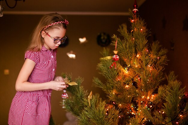 Meisje dat Kerstmisboom met speelgoed en snuisterijen verfraait