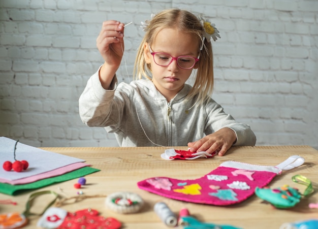 Meisje dat kerstviltdecoratie maakt, kind nieuwjaarsdecor van vilt maakt