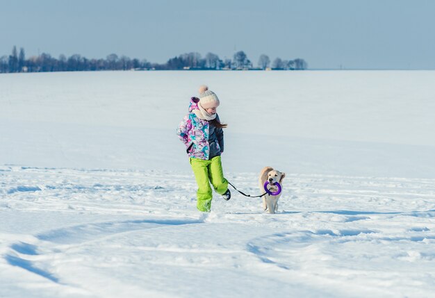 Meisje dat met hond in sneeuw loopt