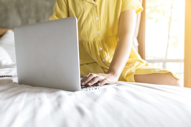 Meisje dat met laptop aan haar bed werkt