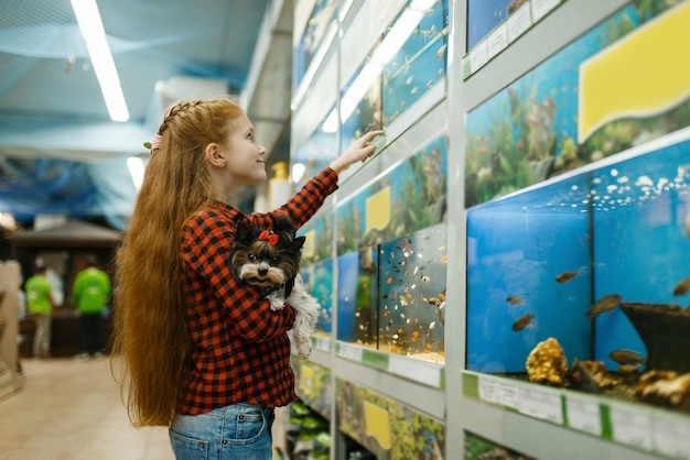 Meisje dat met puppy vissen in aquarium bekijkt