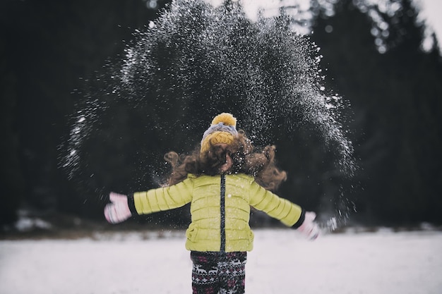 Foto meisje dat met sneeuw speelt.