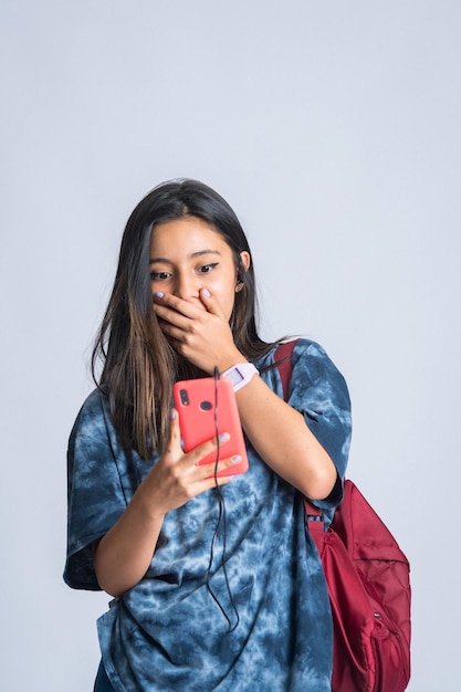 meisje dat naar haar telefoon kijkt en haar verbazing uit over de aanbiedingen die ze heeft gevonden. verbaasd kijken