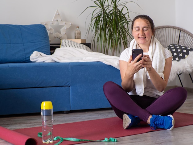 Foto meisje dat op de telefoon kijkt na thuis yoga te hebben beoefend