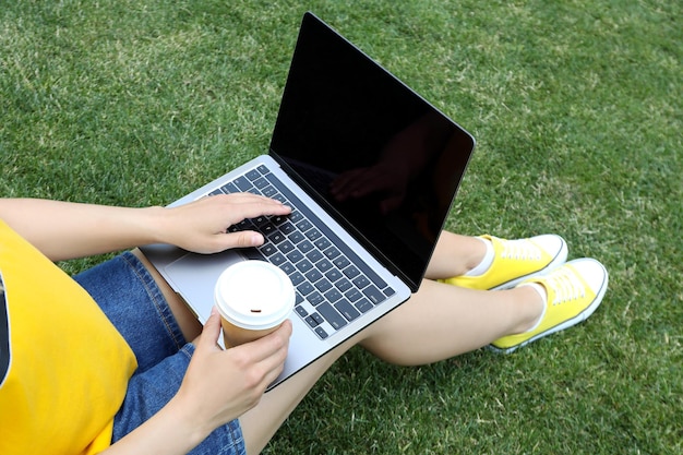 Meisje dat op laptop werkt en buiten op gras zit