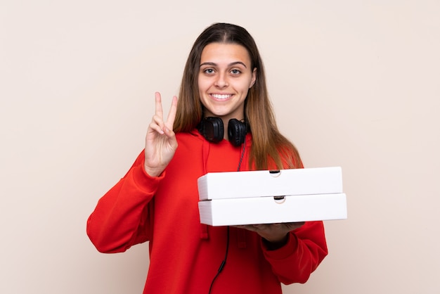 Meisje dat pizzadozen over geïsoleerde muur vangt