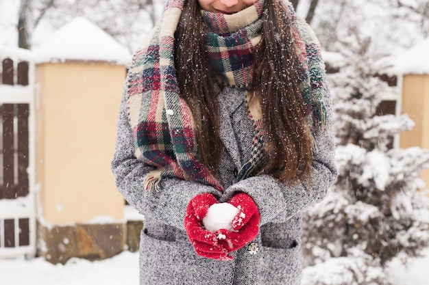 Meisje dat rode behandelde handschoenen draagt die sneeuw met Vrolijke Kerstmisgroet houden