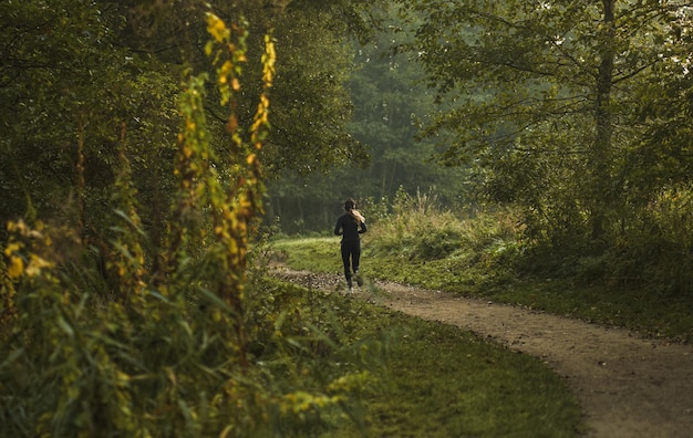 Meisje dat 's ochtends in het park rent Achteraanzicht Fitte vrouw doet haar ochtendoefening buiten