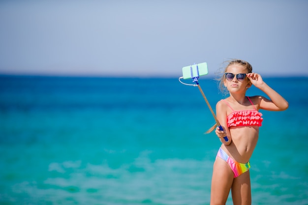 Meisje dat selfie door haar smartphone op het strand neemt.