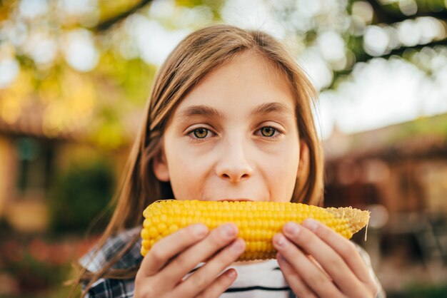 Meisje dat suikermaïs eet openlucht