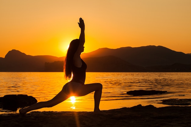 Meisje dat yoga doet door de oceaan.