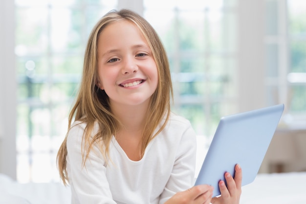 Meisje die de zitting van tabletpc op haar bed gebruiken