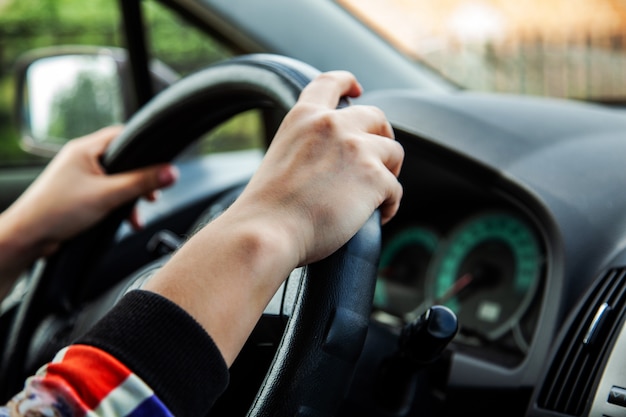 Meisje die een auto, handen van een meisje op het wiel drijven