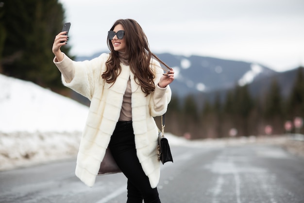 Meisje die foto van haar zelf op smartphone op de winterbergen nemen