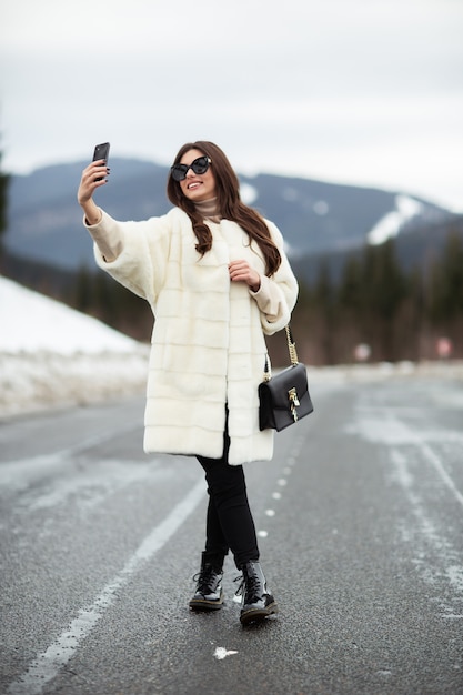 Meisje die foto van haar zelf op smartphone op de winterbergen nemen