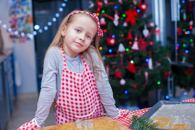 Meisje die in vuisthandschoenen Kerstmispeperkoekkoekjes bakken