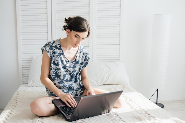 Meisje die laptop op het bed bekijken