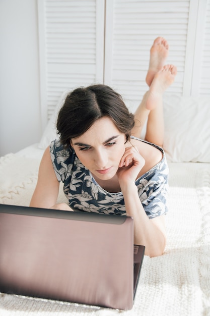 Meisje die laptop op het bed bekijken