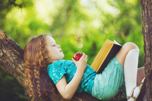 Meisje die op grote boom liggen en leest het boek.