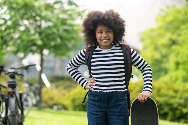 Meisje die plezier heeft met een skateboard in de zomer, schoolmeisje dat geniet van skateboarden in het park.