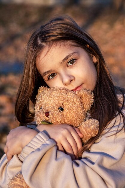 Meisje die teddybeer knuffelt en naar de camera kijkt