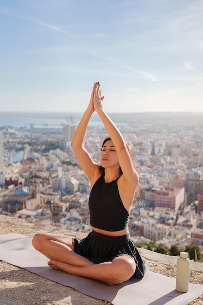 Foto meisje doet yoga buiten op de achtergrond van de stad en de zee