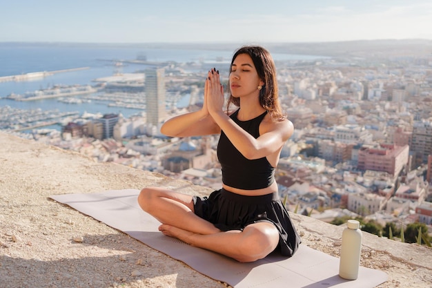 Foto meisje doet yoga buiten op de achtergrond van de stad en de zee