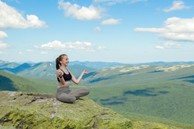 Meisje doet yoga oefening lotus houding op de top van de berg