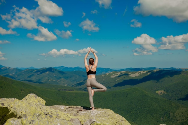 Meisje doet yoga oefening lotus houding op de top van de berg.