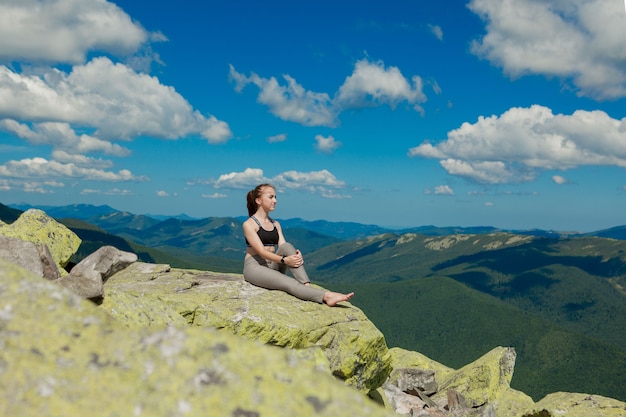 Meisje doet yoga oefening lotus houding op de top van de berg.