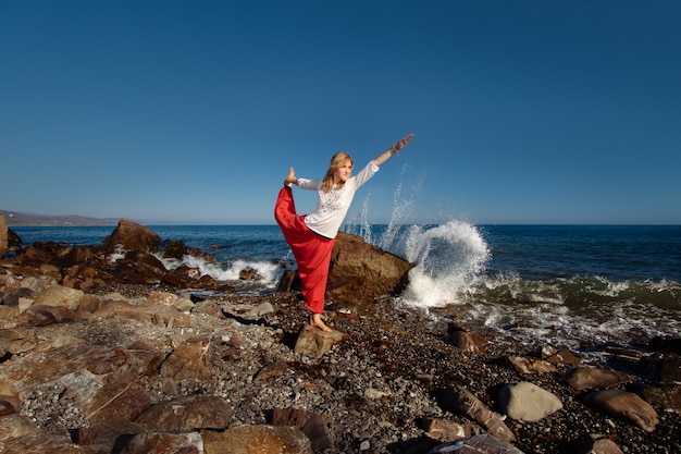 Meisje doet yoga op de heuvel. Oceaan in golven