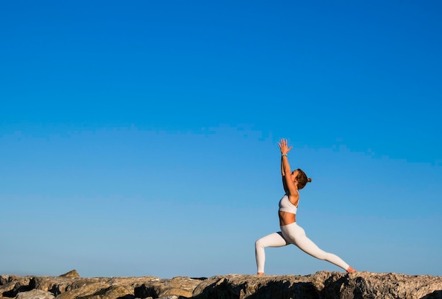 Meisje doet yoga op de rotsen op het strand