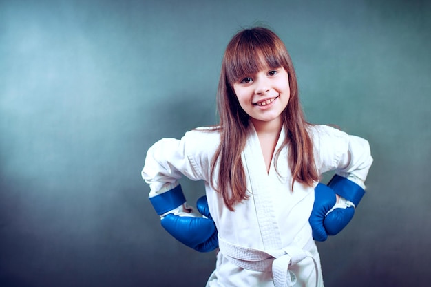 Meisje draagt een karate-uniform en blauwe bokshandschoen