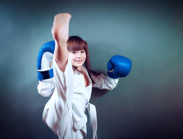 Meisje draagt een karate-uniform en blauwe bokshandschoen