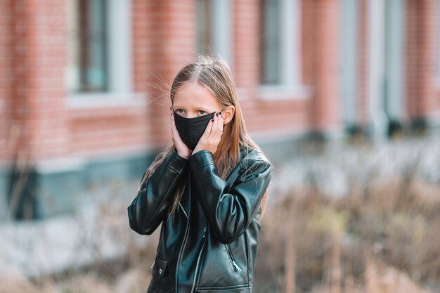 Meisje draagt een masker op een achtergrond van een modern gebouw,