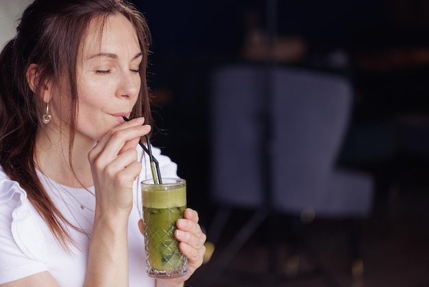 Meisje drinkt gezonde verse cocktail in modern café