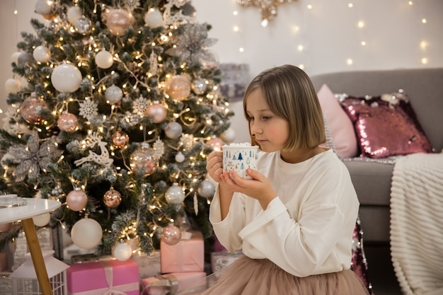 Meisje drinkt koffie met marshmallow in feestelijke woonkamer