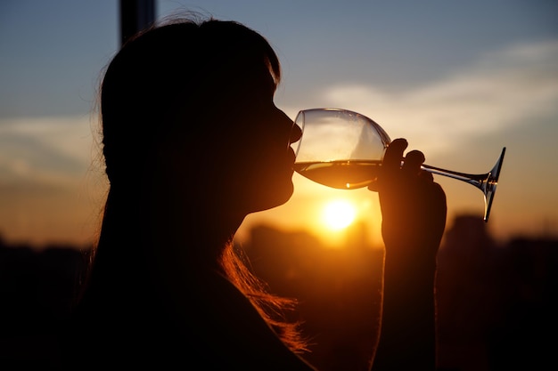 Meisje drinkt uit een glas bij zonsondergang