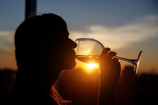 Meisje drinkt uit een glas bij zonsondergang