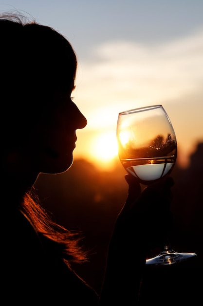Meisje drinkt uit een glas bij zonsondergang